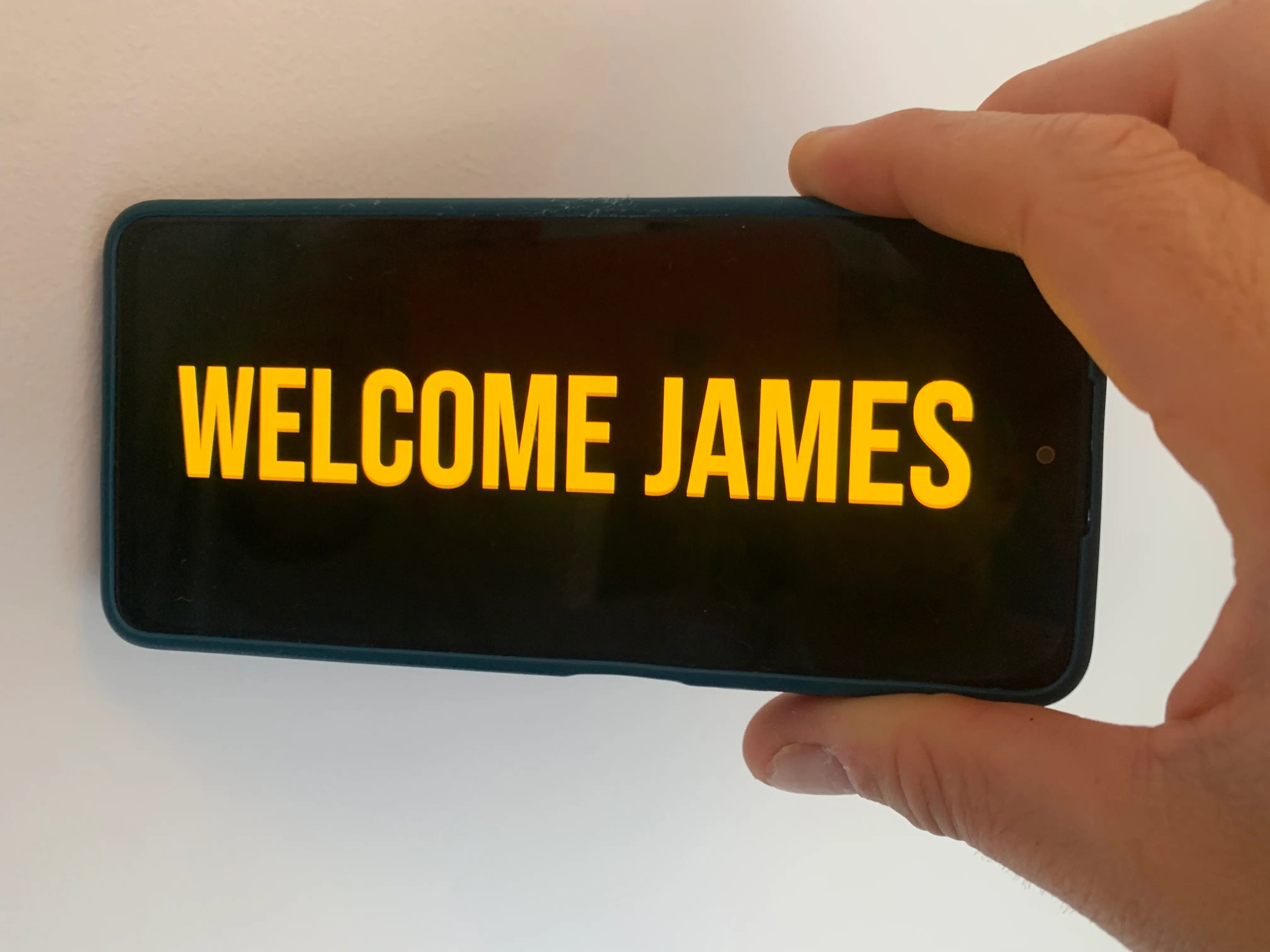 Phone showing a fullscreen pickup sign with the message Welcome James