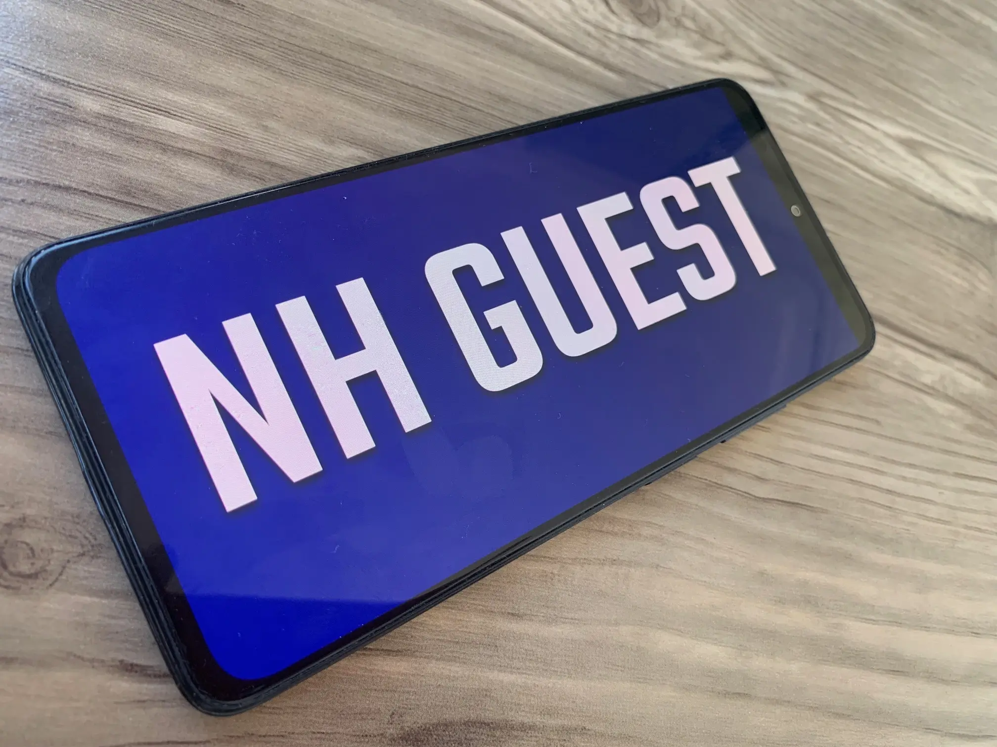 Phone showing a professional airport pickup sign with the message RadAppsLab Guest